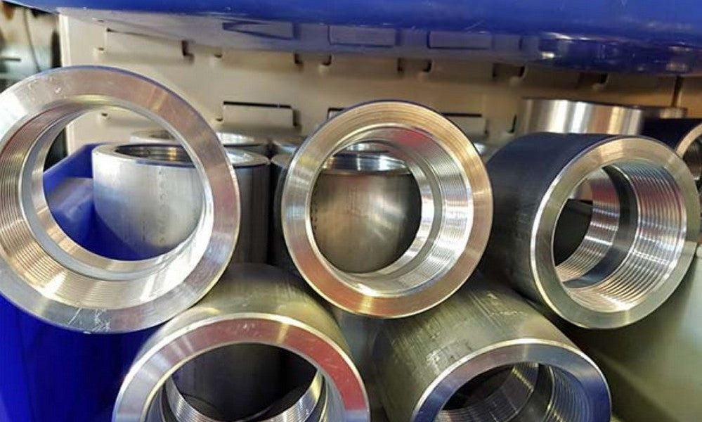 Circular aluminium fittings on top of one another in a blue container on a shelf.