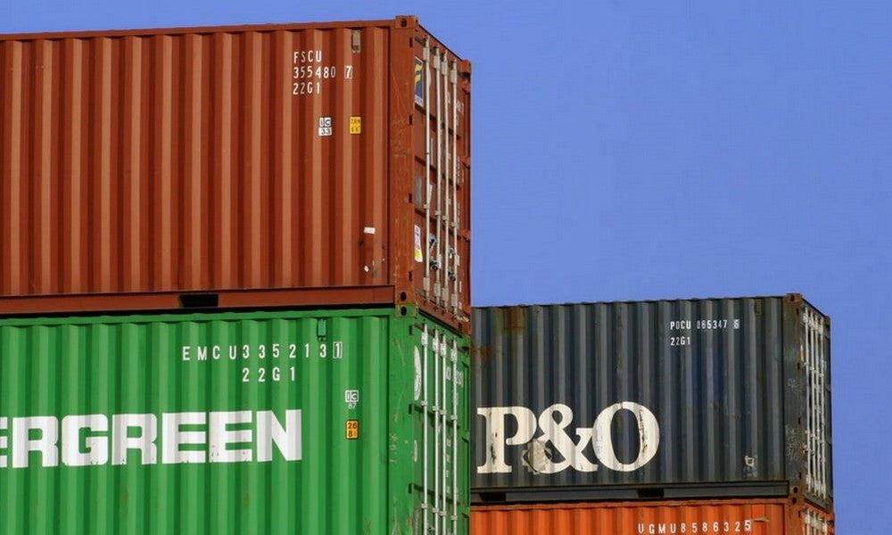 Different coloured shipping containers stacked up into the sky.