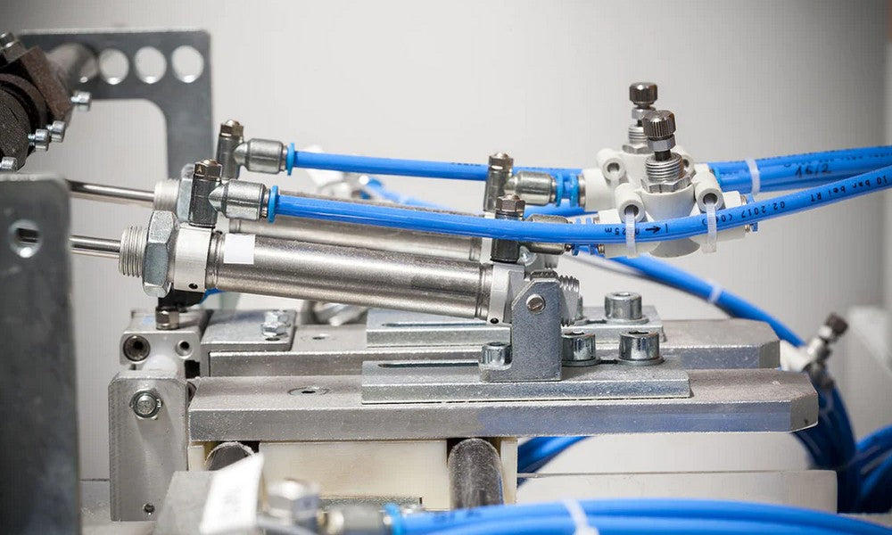 A pneumatic connection between tiny valves and blue tubing.