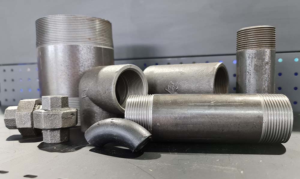 A collection of fittings that are dark grey sitting together on a black shelf.