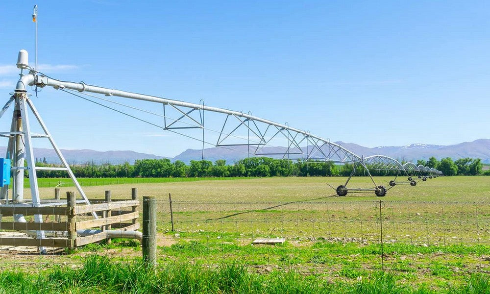 An irrigation system with pumped water in use on a farm in Canterbury. Green pastures with rolling hills in the far background.