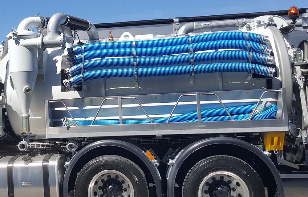 Blue hoses on the side of a vacuum truck.