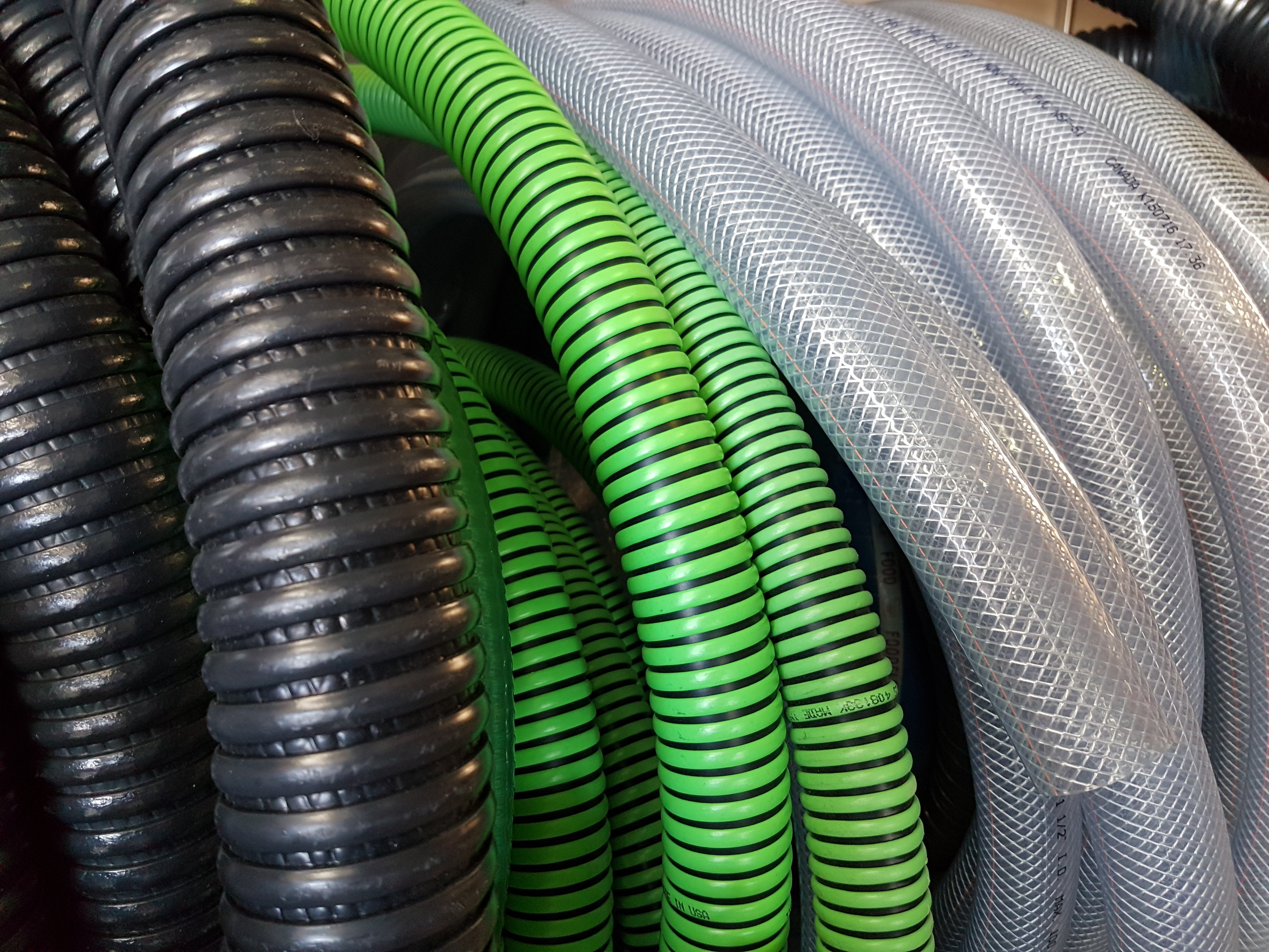 A collection of black, green, and clear hoses rolled together. 